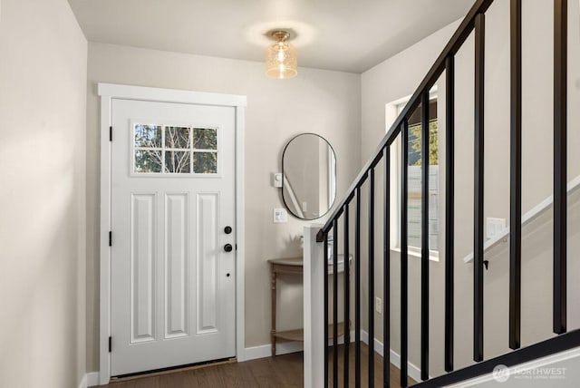 foyer with baseboards, wood finished floors, and stairway