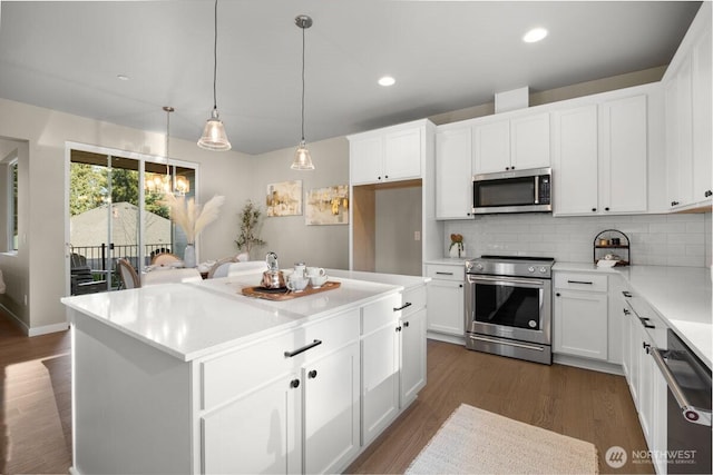 kitchen with dark wood-style flooring, appliances with stainless steel finishes, light countertops, a center island, and backsplash