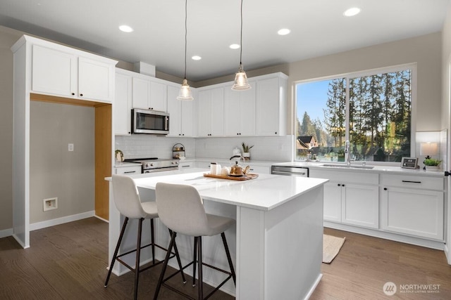kitchen with backsplash, appliances with stainless steel finishes, a center island, a sink, and white cabinetry