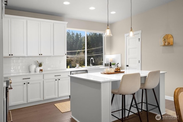 kitchen featuring a sink, tasteful backsplash, a kitchen island, and a kitchen bar