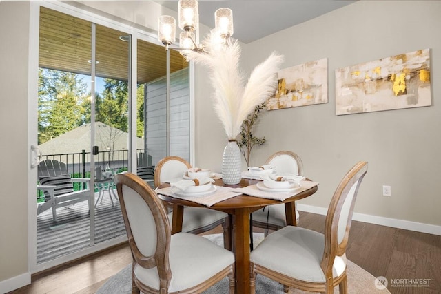 dining room featuring baseboards, wood finished floors, and a chandelier