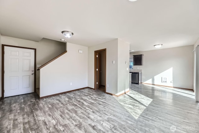 unfurnished living room with baseboards and wood finished floors