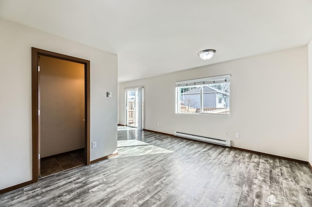 spare room featuring baseboards, baseboard heating, and wood finished floors