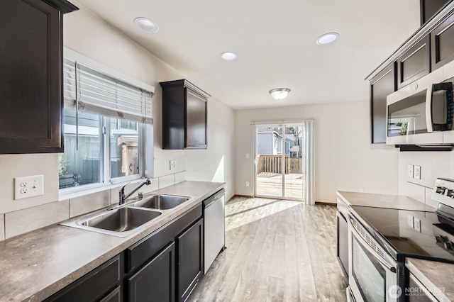 kitchen with stainless steel appliances, recessed lighting, light wood-style floors, a sink, and baseboards