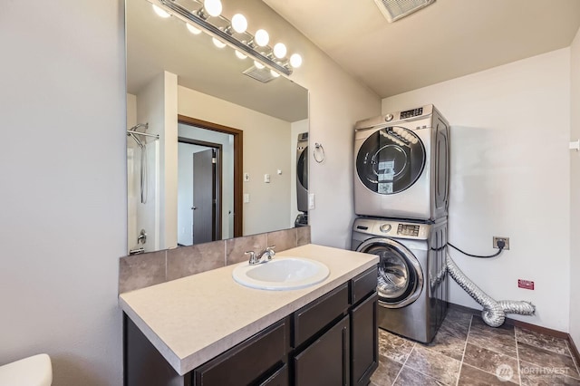 laundry room with laundry area, a sink, visible vents, baseboards, and stacked washing maching and dryer