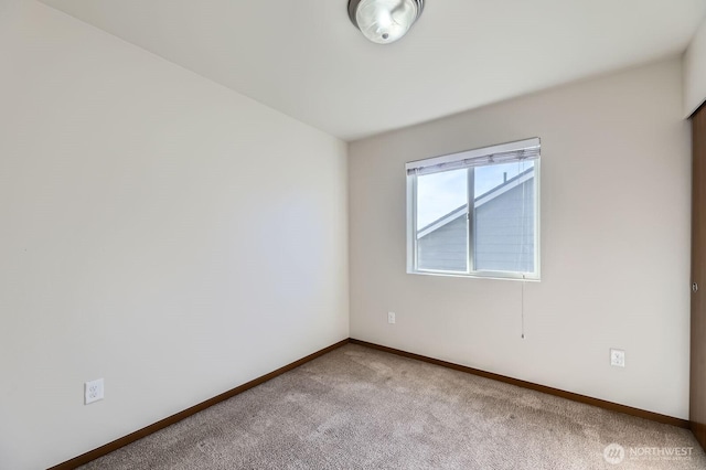 carpeted spare room featuring baseboards