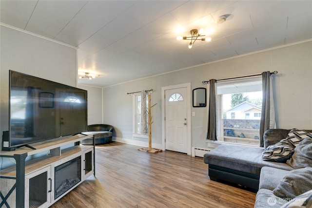 living room featuring baseboards, a baseboard radiator, ornamental molding, and wood finished floors