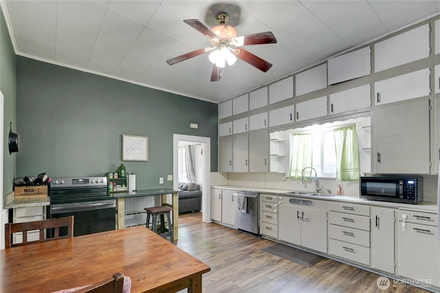 kitchen featuring crown molding, stainless steel appliances, light wood-style floors, a sink, and ceiling fan