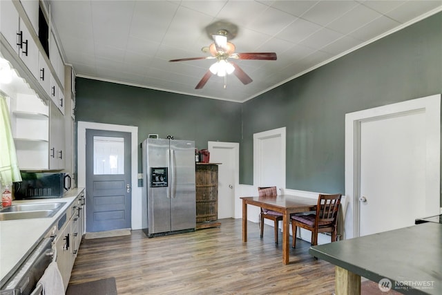 kitchen featuring black microwave, wood finished floors, white cabinetry, stainless steel fridge with ice dispenser, and crown molding