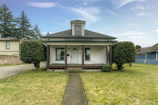 bungalow-style home featuring covered porch, roof with shingles, and a front yard