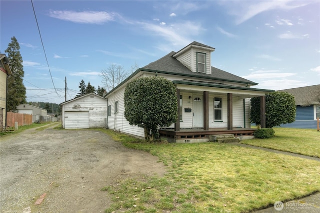 view of front of home with an outbuilding, a detached garage, dirt driveway, a porch, and a front lawn