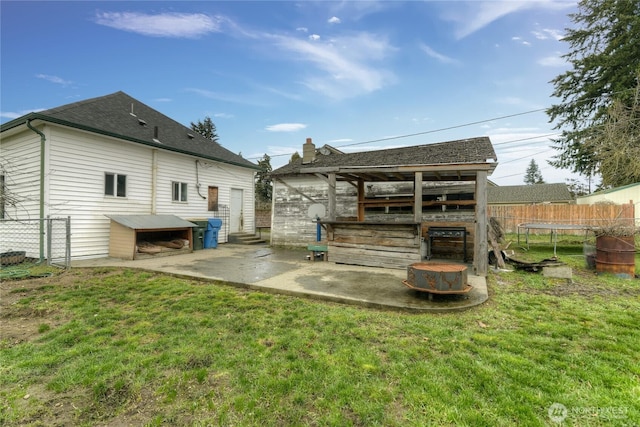 rear view of house with a yard, a trampoline, a patio area, and fence