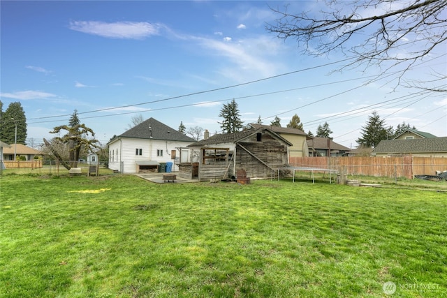 back of property featuring an outbuilding, a yard, a trampoline, and a fenced backyard