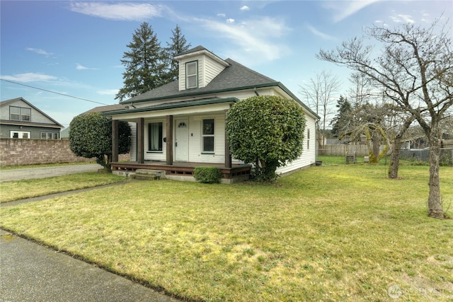 view of front of house featuring a front lawn, fence, a porch, and roof with shingles