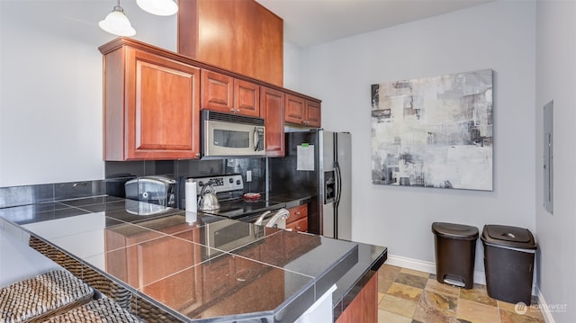 kitchen with backsplash, hanging light fixtures, electric panel, kitchen peninsula, and stainless steel appliances