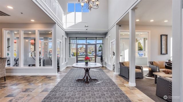 foyer entrance with an inviting chandelier, a healthy amount of sunlight, and a high ceiling