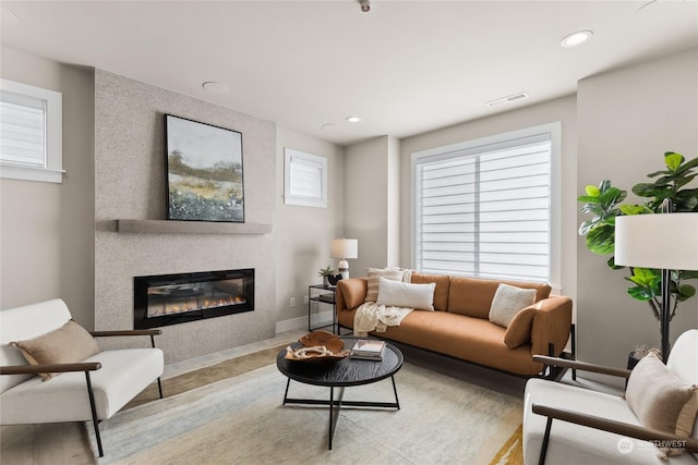 living room with a fireplace and light wood-type flooring