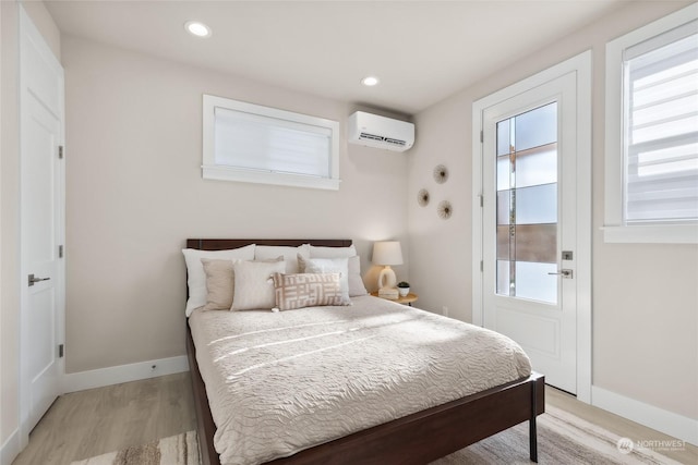 bedroom with an AC wall unit and light wood-type flooring