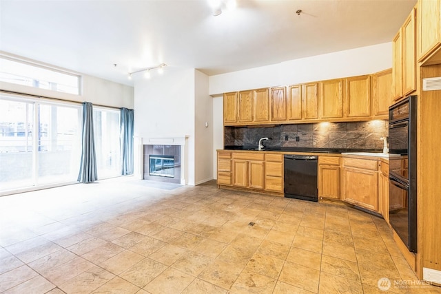 kitchen featuring sink, backsplash, a fireplace, and black appliances