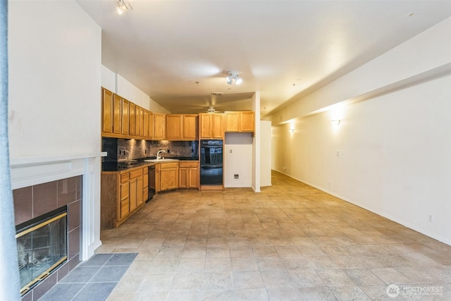 kitchen featuring backsplash, a tiled fireplace, sink, and black appliances