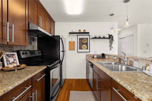 kitchen featuring sink, light stone counters, light hardwood / wood-style flooring, appliances with stainless steel finishes, and pendant lighting