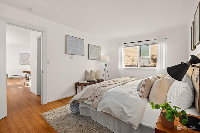 bedroom featuring a baseboard heating unit and light hardwood / wood-style flooring