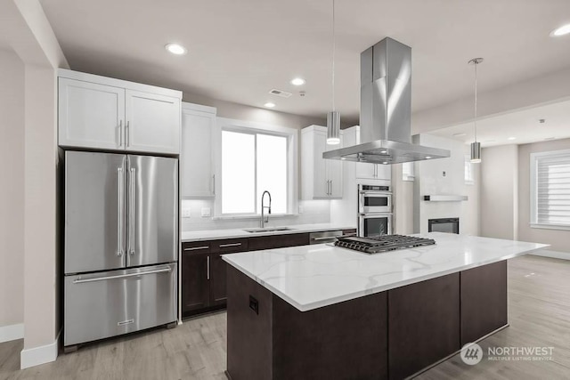 kitchen featuring hanging light fixtures, island exhaust hood, appliances with stainless steel finishes, and a center island