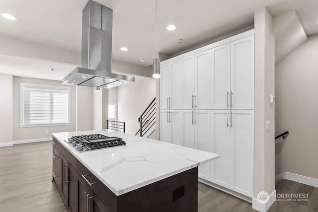 kitchen featuring white cabinetry, island exhaust hood, stainless steel gas cooktop, and pendant lighting