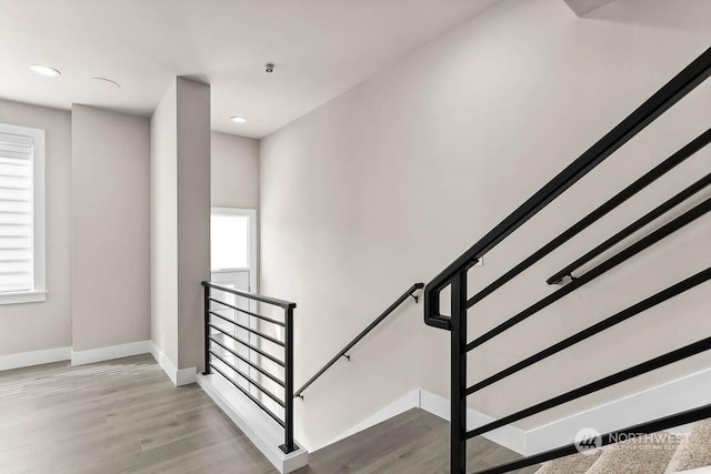 stairway featuring plenty of natural light and hardwood / wood-style floors