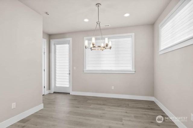 unfurnished dining area featuring wood-type flooring and a chandelier