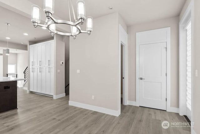 unfurnished dining area with a wealth of natural light, a notable chandelier, and light hardwood / wood-style flooring