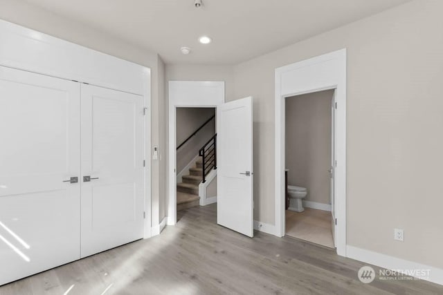 unfurnished bedroom featuring light hardwood / wood-style flooring, connected bathroom, and a closet