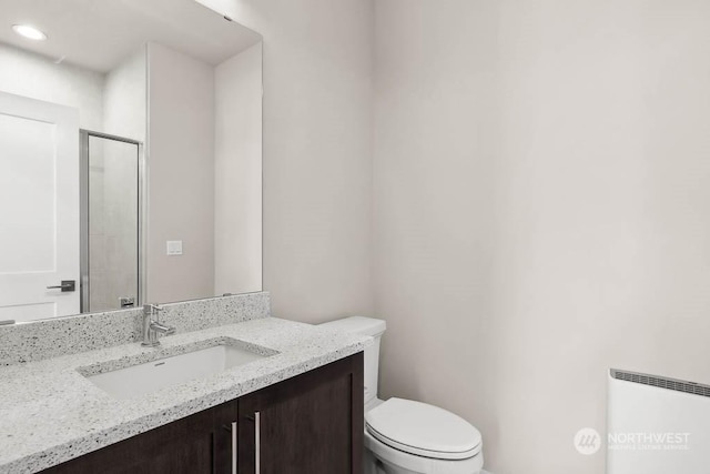 bathroom featuring vanity, toilet, a shower with door, and radiator heating unit