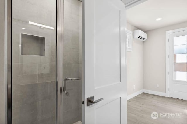 bathroom with hardwood / wood-style flooring, an enclosed shower, and a wall unit AC