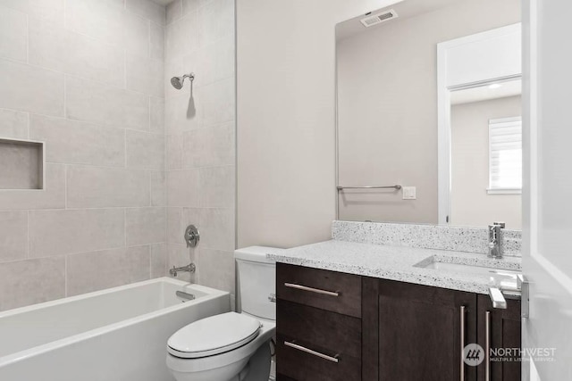 full bathroom featuring vanity, tiled shower / bath, and toilet