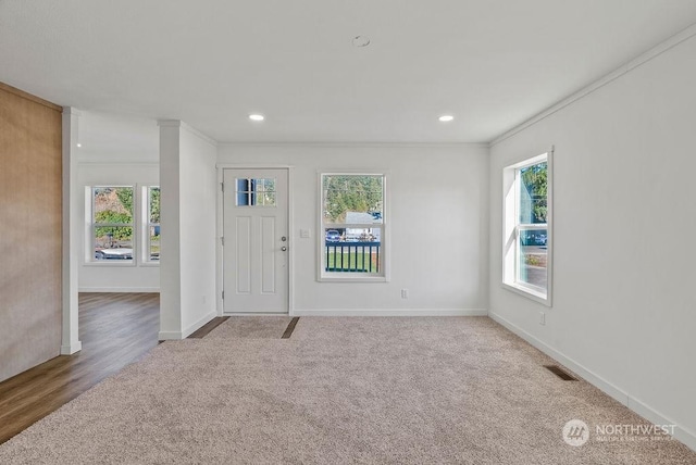 foyer entrance featuring crown molding and carpet flooring