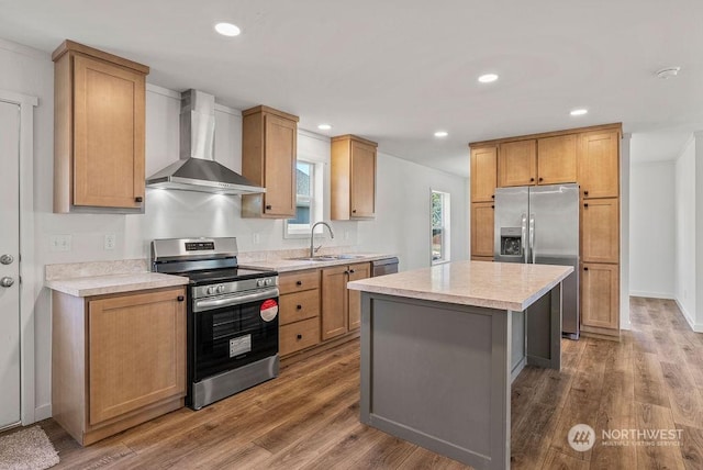 kitchen with wood-type flooring, sink, a center island, stainless steel appliances, and wall chimney exhaust hood