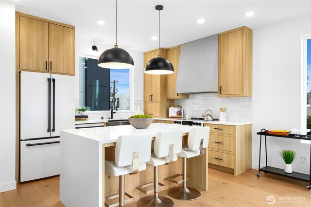 kitchen with freestanding refrigerator, light wood finished floors, decorative backsplash, light countertops, and recessed lighting