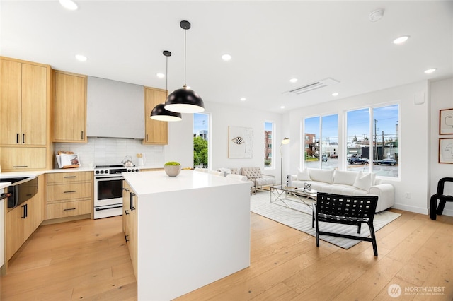 kitchen with light brown cabinets, electric stove, open floor plan, light wood-type flooring, and recessed lighting