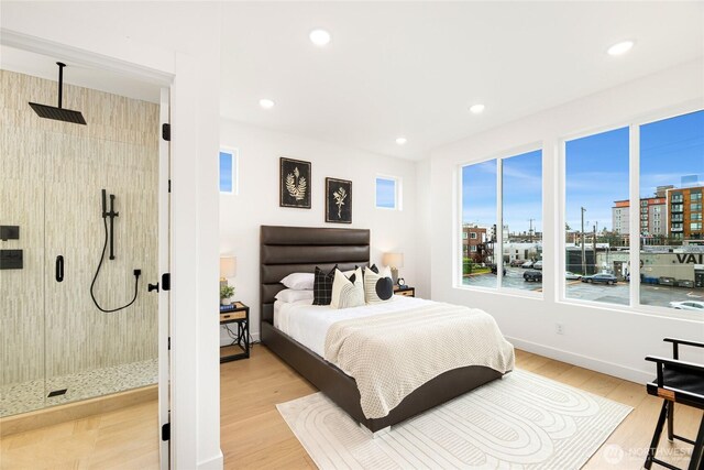 bedroom with light wood-style flooring, recessed lighting, baseboards, and a view of city