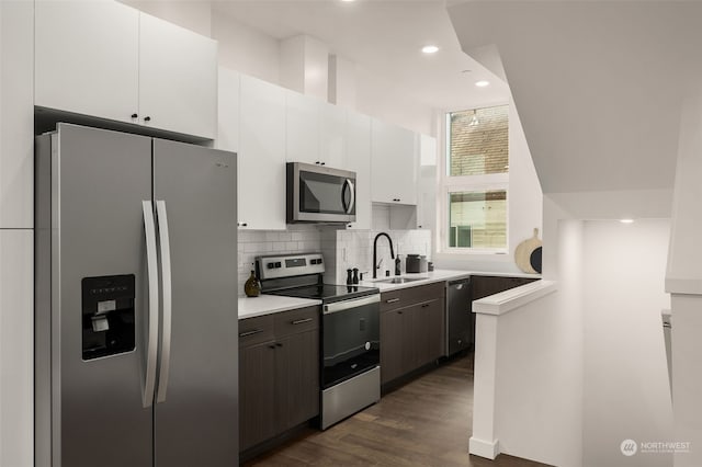 kitchen with sink, white cabinetry, dark brown cabinets, stainless steel appliances, and decorative backsplash