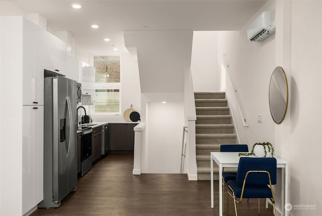 kitchen with appliances with stainless steel finishes, a wall mounted air conditioner, and dark hardwood / wood-style flooring