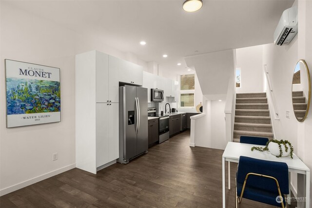 kitchen with white cabinetry, appliances with stainless steel finishes, dark hardwood / wood-style floors, and a wall mounted AC