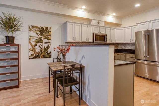 kitchen with white cabinetry, tasteful backsplash, light wood-type flooring, ornamental molding, and appliances with stainless steel finishes