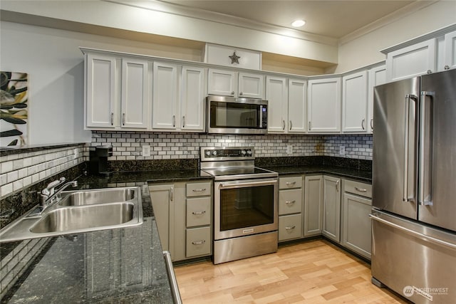 kitchen featuring sink, crown molding, stainless steel appliances, light hardwood / wood-style floors, and dark stone counters