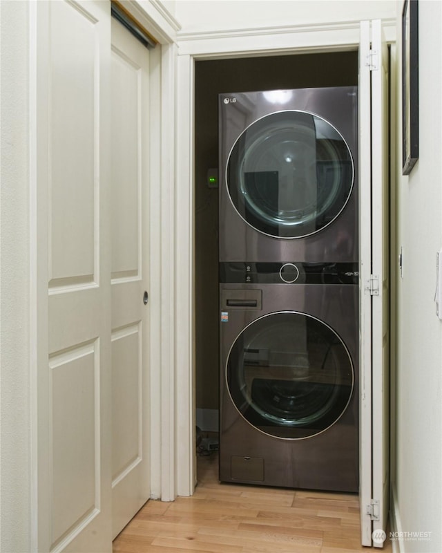 clothes washing area with stacked washer / drying machine and light hardwood / wood-style floors