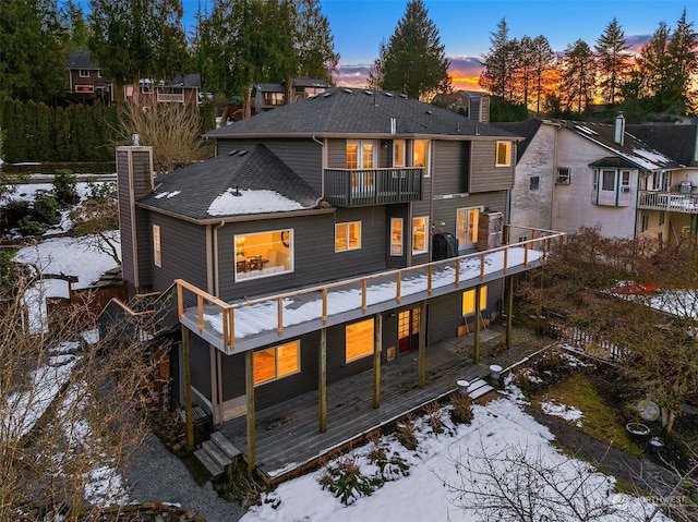 snow covered property featuring a balcony and a deck