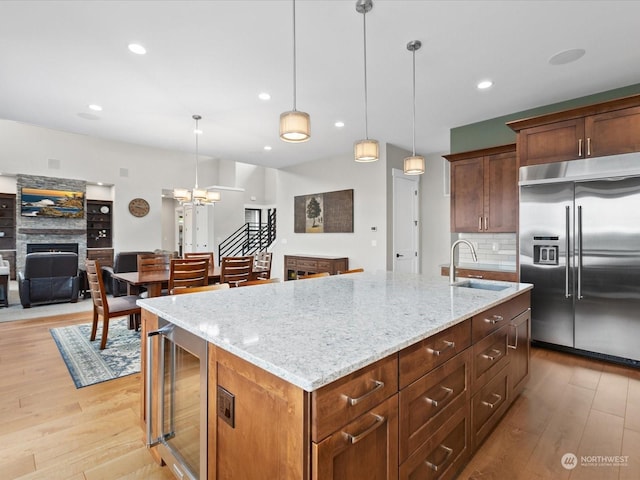 kitchen with light wood-style flooring, a fireplace, a sink, stainless steel built in fridge, and wine cooler