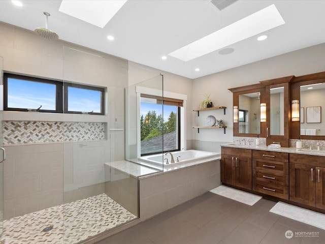 full bathroom featuring a tile shower, visible vents, a skylight, and a garden tub