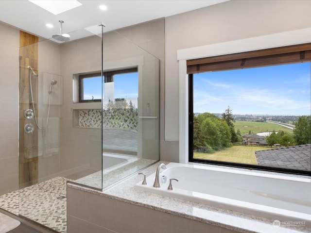 full bath with a garden tub, a skylight, and tiled shower